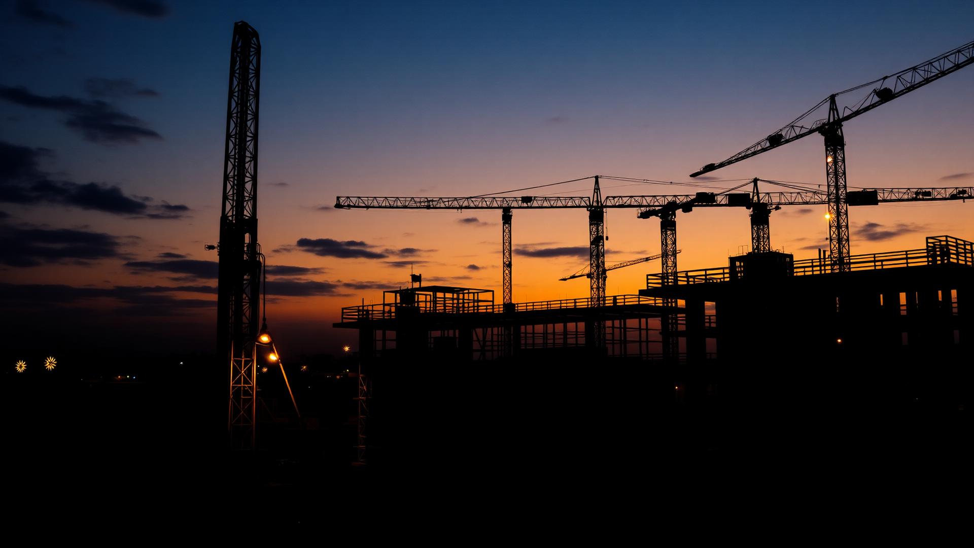 Construction site with cranes and drilling rig at dusk
